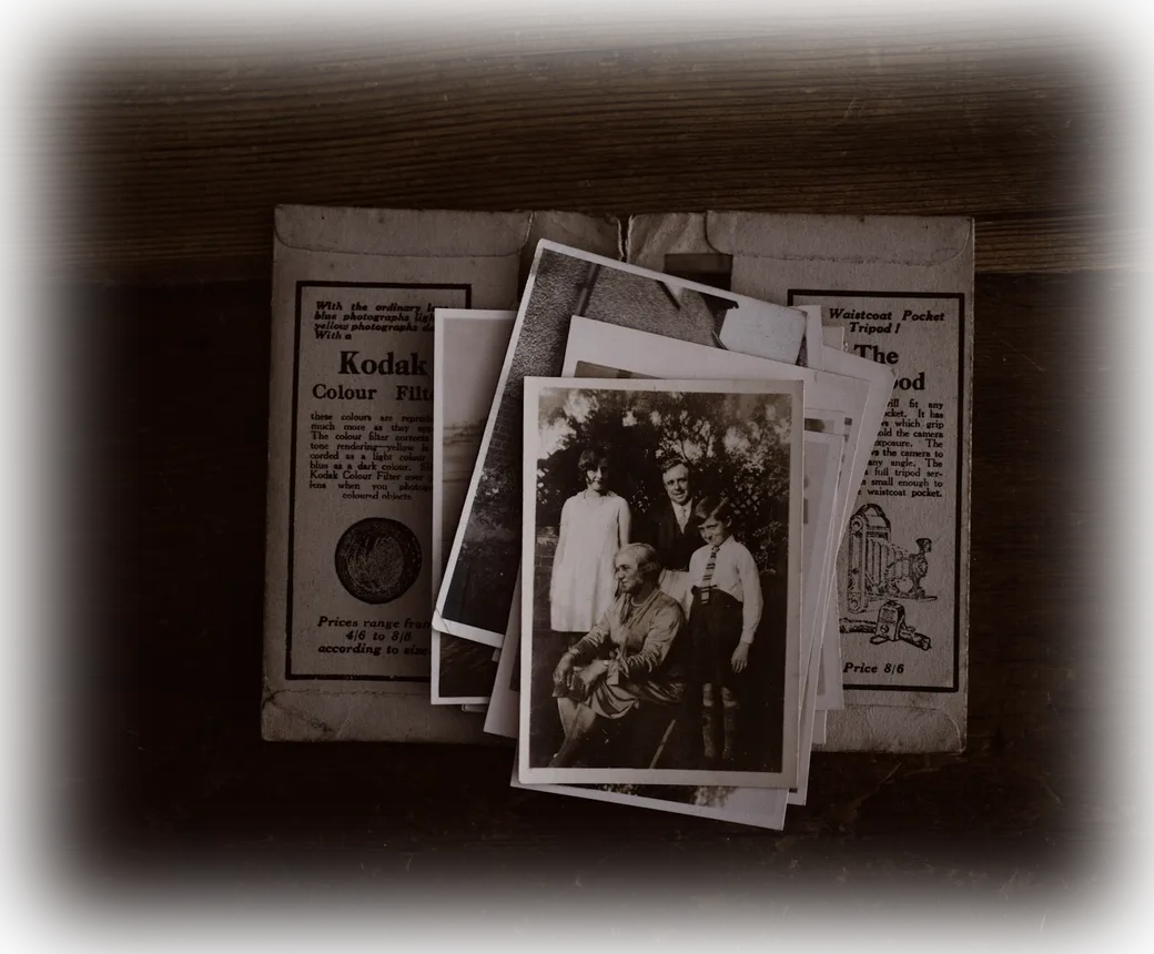 A scatter of old family photographs beside a newspaper obituary clipping